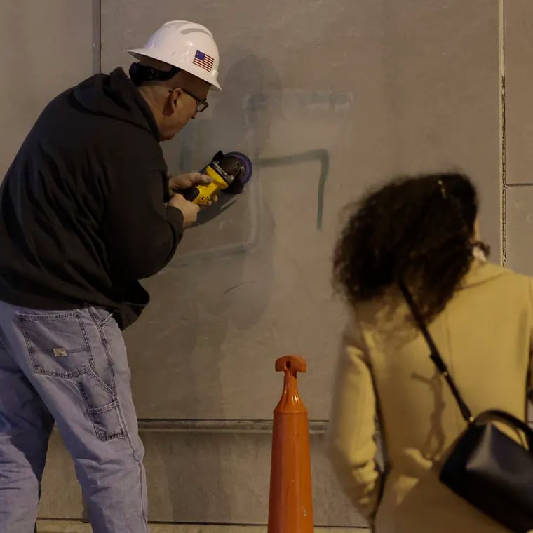 A spray-painted swastika is removed from a wall adjacent to the Horwitz-Wasserman Holocaust Memorial Plaza on the Ben Franklin Parkway in January. In the latest act of antisemitic vandalism, a swastika was painted on a sign Saturday night at Temple Beth Hillel-Beth El in Wynnewood.