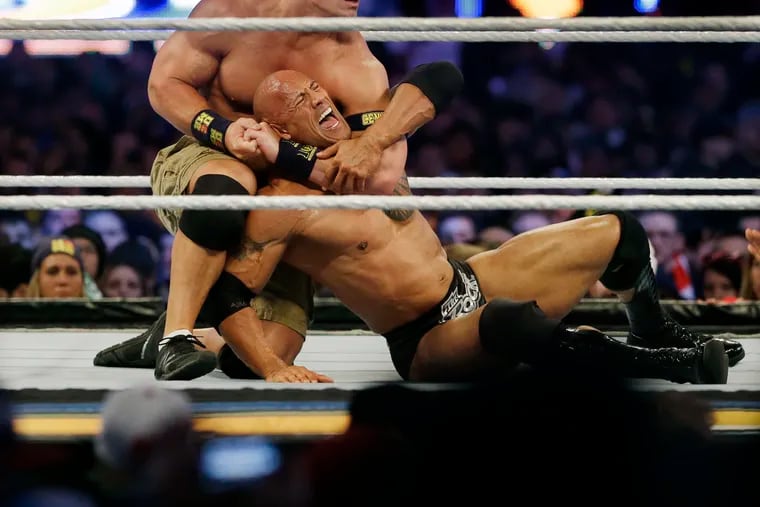 Wrestler John Cena, top, chokes Dwayne "The Rock" Johnson at a Wrestlemania event on April 7, 2013, in East Rutherford, N.J. It is a name that has become almost synonymous with professional wrestling but its bearer, Dwayne Johnson, has never legally owned "The Rock." (AP Photo/Mel Evans, File)